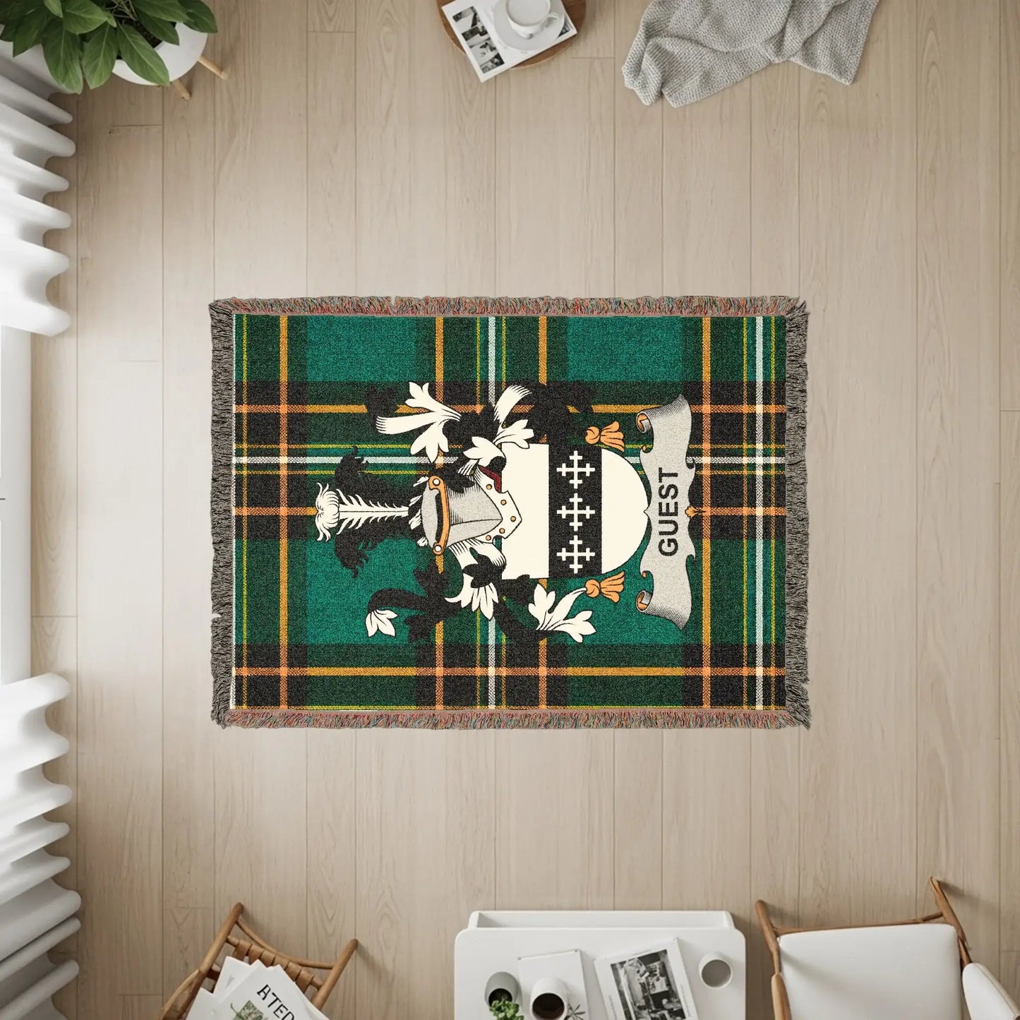 Woven blanket with a green plaid pattern and the Guest family crest.