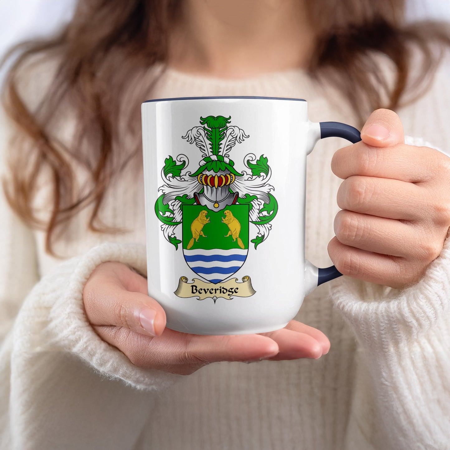 White mug with Beveridge family crest held by person in white sweater.