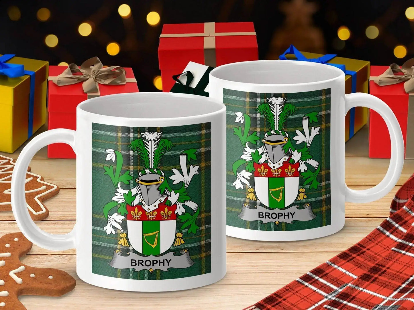 Two white mugs with Brophy family crest on green plaid background surrounded by Christmas gifts and gingerbread cookies