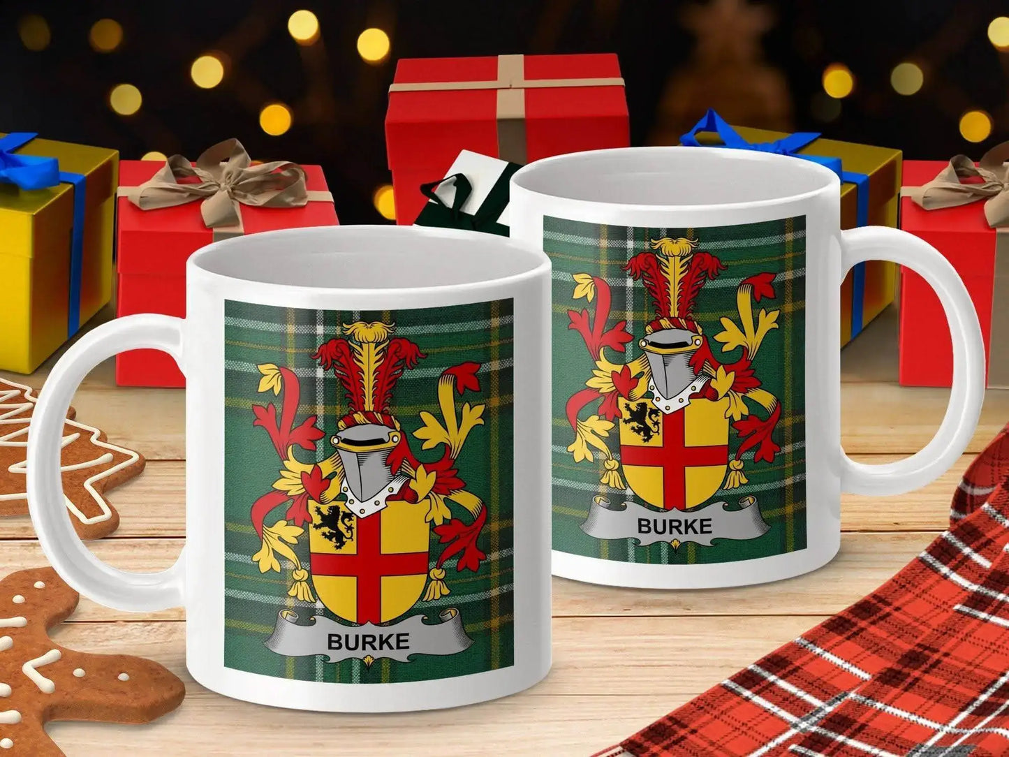 Two white mugs with Burke family crest on green tartan background surrounded by Christmas gifts and gingerbread cookies