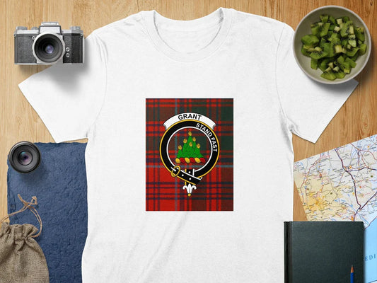 Clan Grant Scottish t-shirt featuring the "Stand Fast" motto and tartan crest design, displayed on a wooden surface.