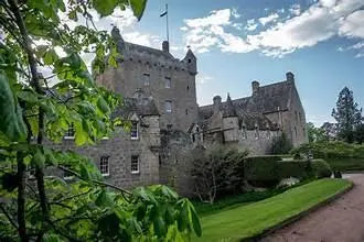 Historic stone castle surrounded by greenery under a partly cloudy blue sky