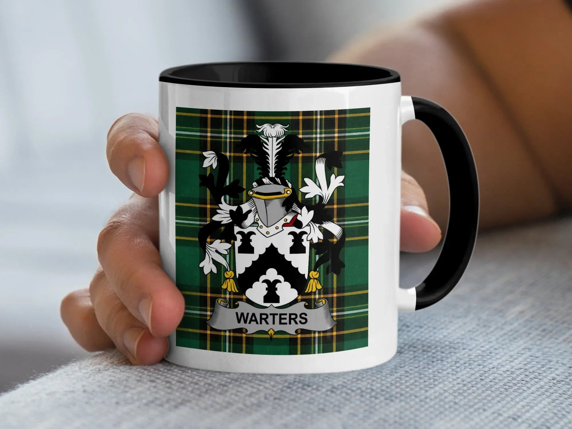 White mug with black rim and handle displaying the "Warters" family crest on a tartan background.