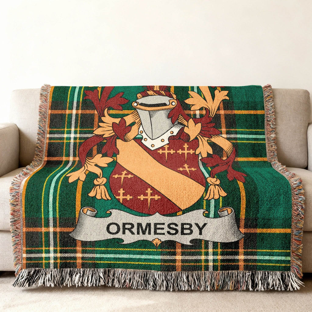 Green tartan blanket with Ormsby family crest on a couch.