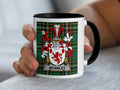 White mug with black rim featuring the McCawley coat of arms on a tartan background.
