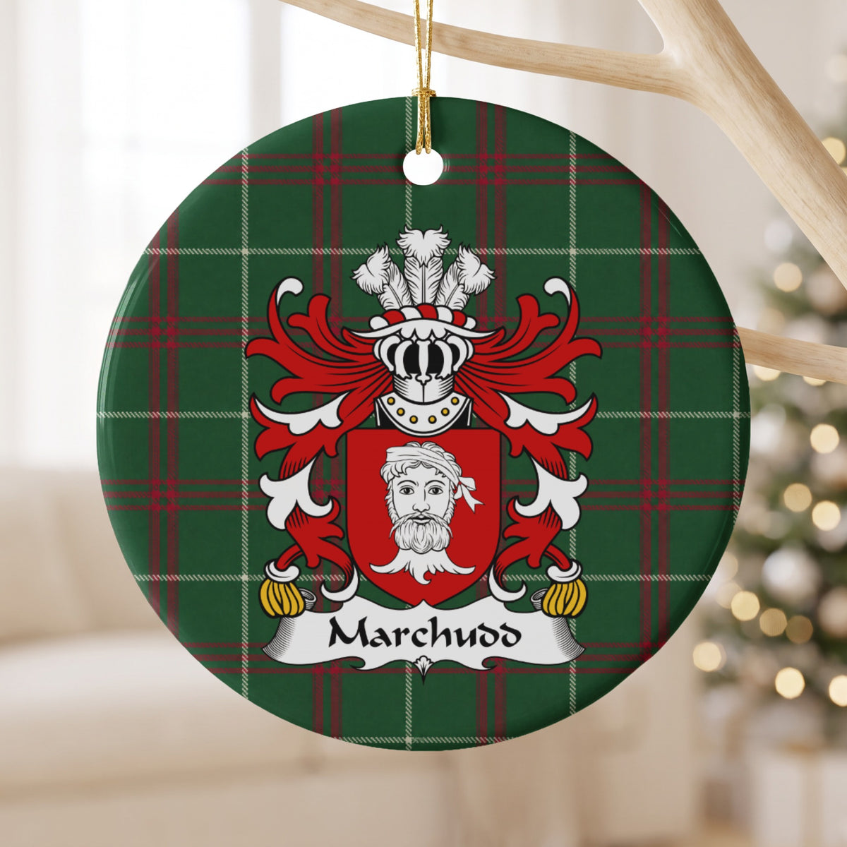 Marchudd ceramic ornament hanging from a pale wooden branch, showing a red shield with a white bearded head on Welsh national tartan.