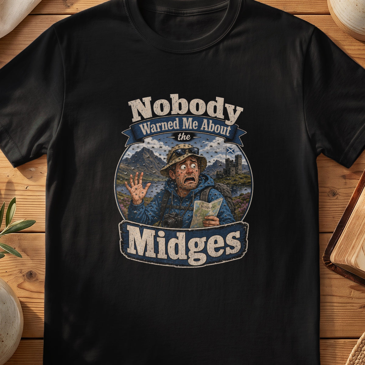 Black Gildan 64000 unisex T-shirt flatlay with Nobody Warned Me About the Midges Scottish graphic design