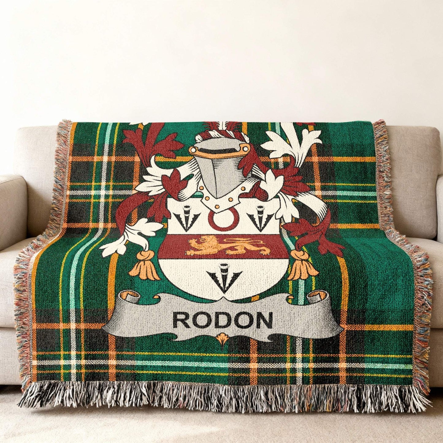 Green tartan throw blanket with Rodon family crest on a couch.