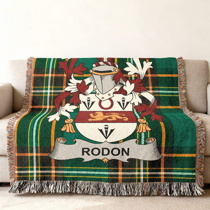 Green tartan throw blanket with Rodon family crest on a couch.