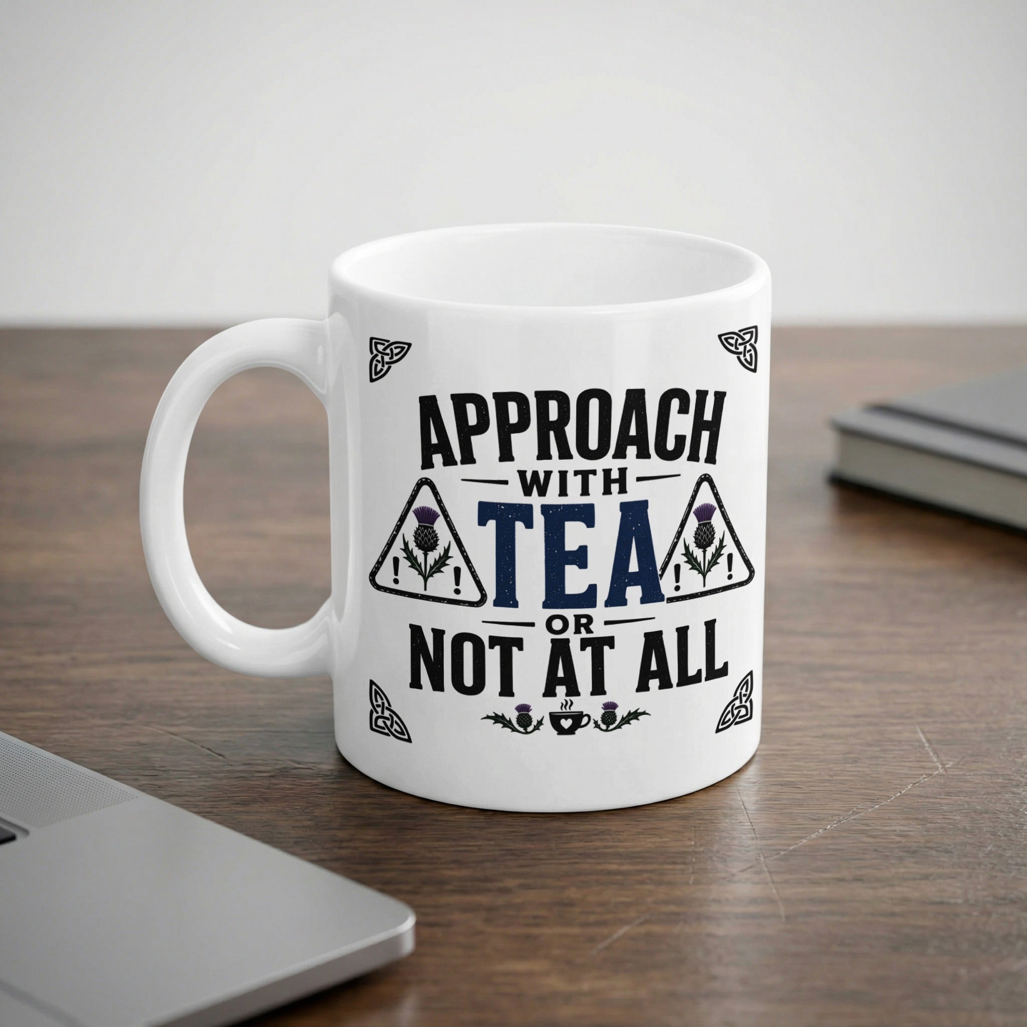 White mug with "Approach with tea or not at all" slogan and Scottish thistle designs.