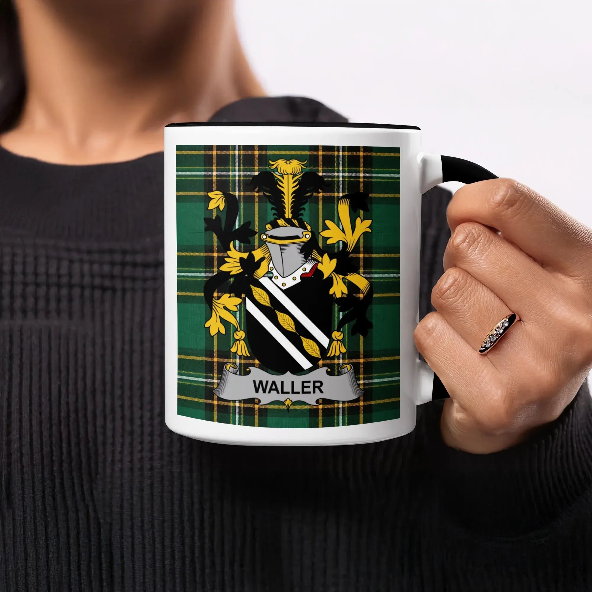 Mug with Waller family crest on green plaid background, held by person.