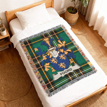 Green tartan blanket with Foord family crest draped on a white bed.