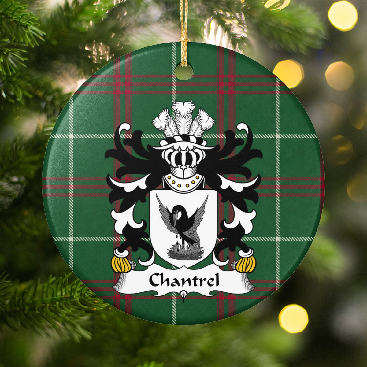 Chantrel ornament hanging among Christmas tree branches and warm lights; a dark bird with raised wings above a nest on a white shield on Welsh national tartan.