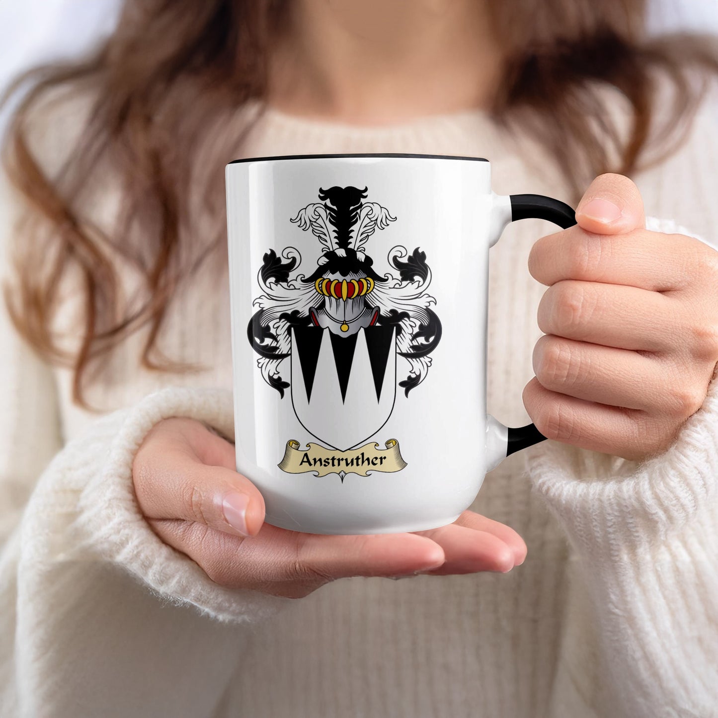 White mug with black rim held by hands, displaying the Anstruther coat of arms.