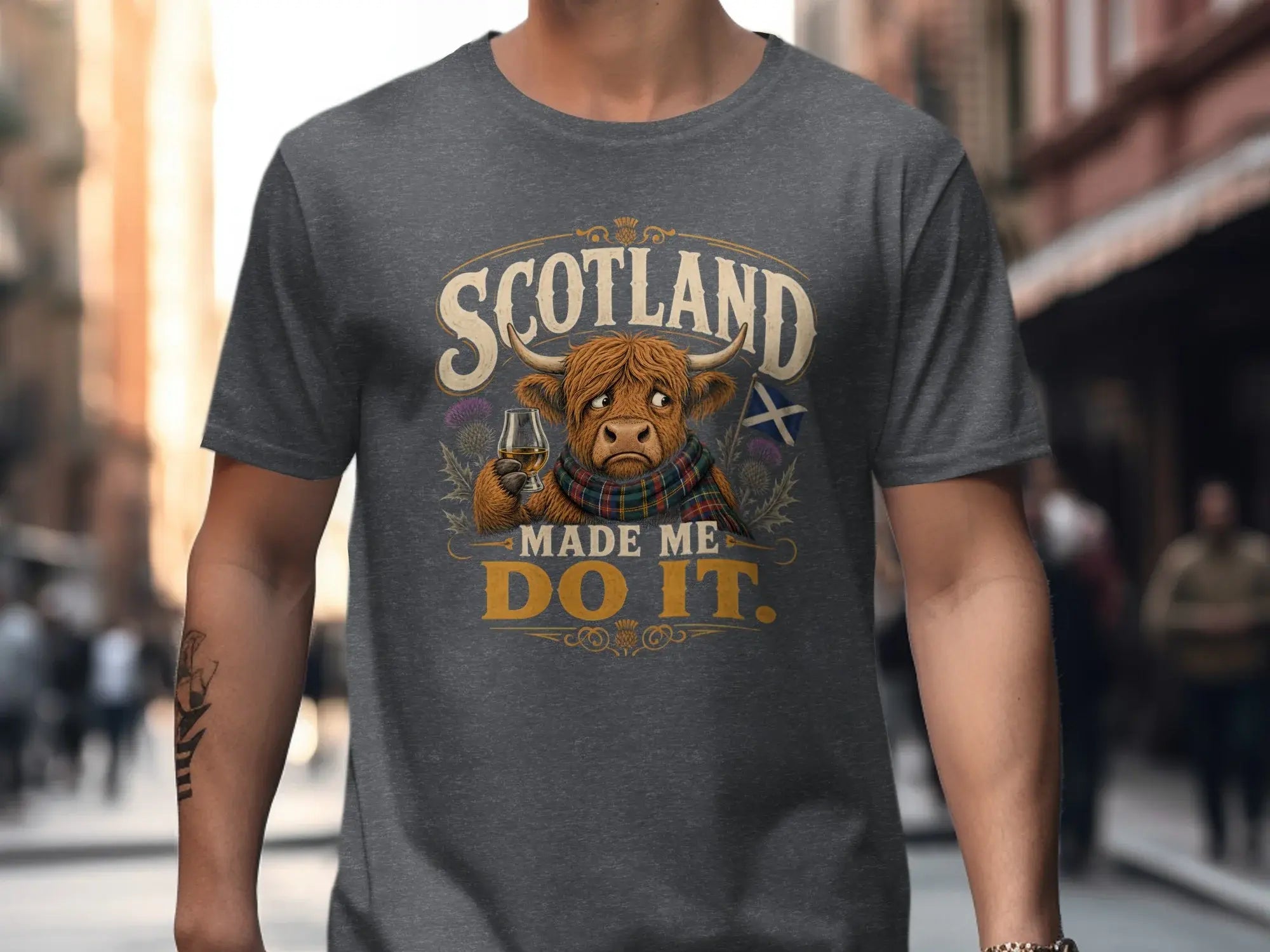 Dark grey t-shirt with "Scotland Made Me Do It" text, Highland cow, and Scottish flag.