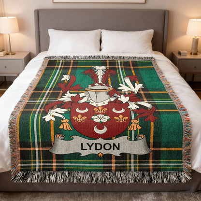 Green tartan blanket with LYDON family crest displayed on a bed.