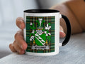 Mug with Wycombe crest on tartan background, held by a hand.