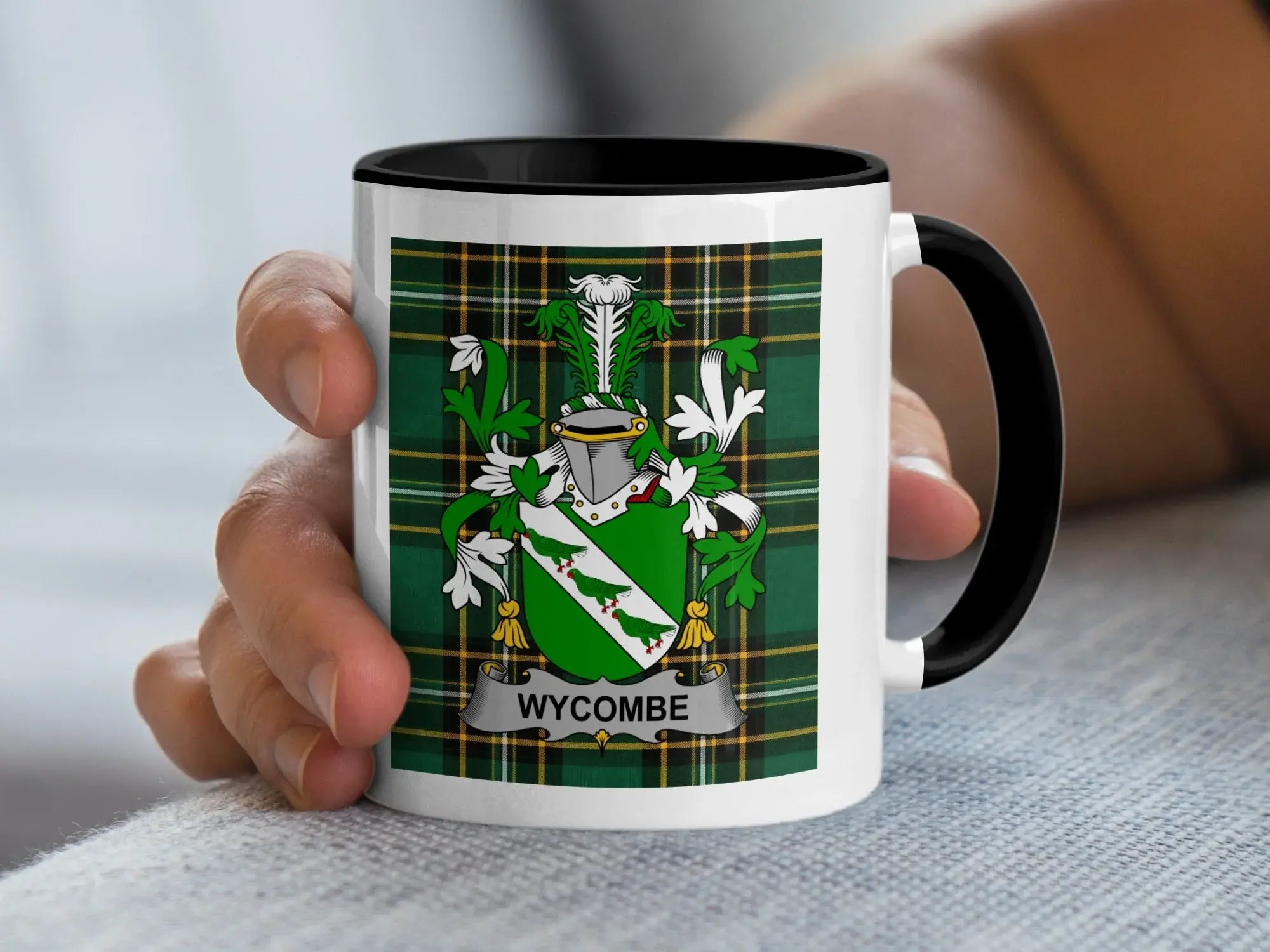 Mug with Wycombe crest on tartan background, held by a hand.