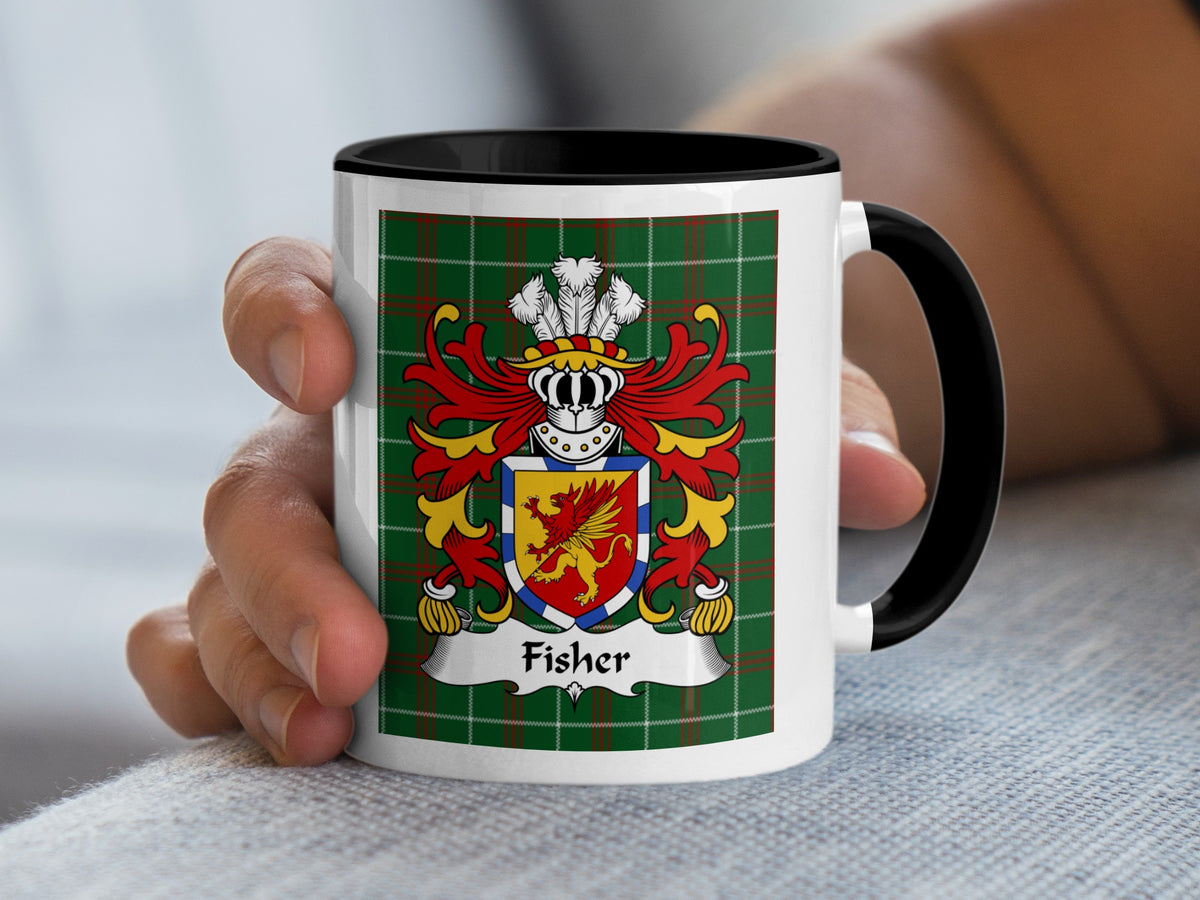 Mug with Fisher coat of arms on green plaid background, held by a hand.