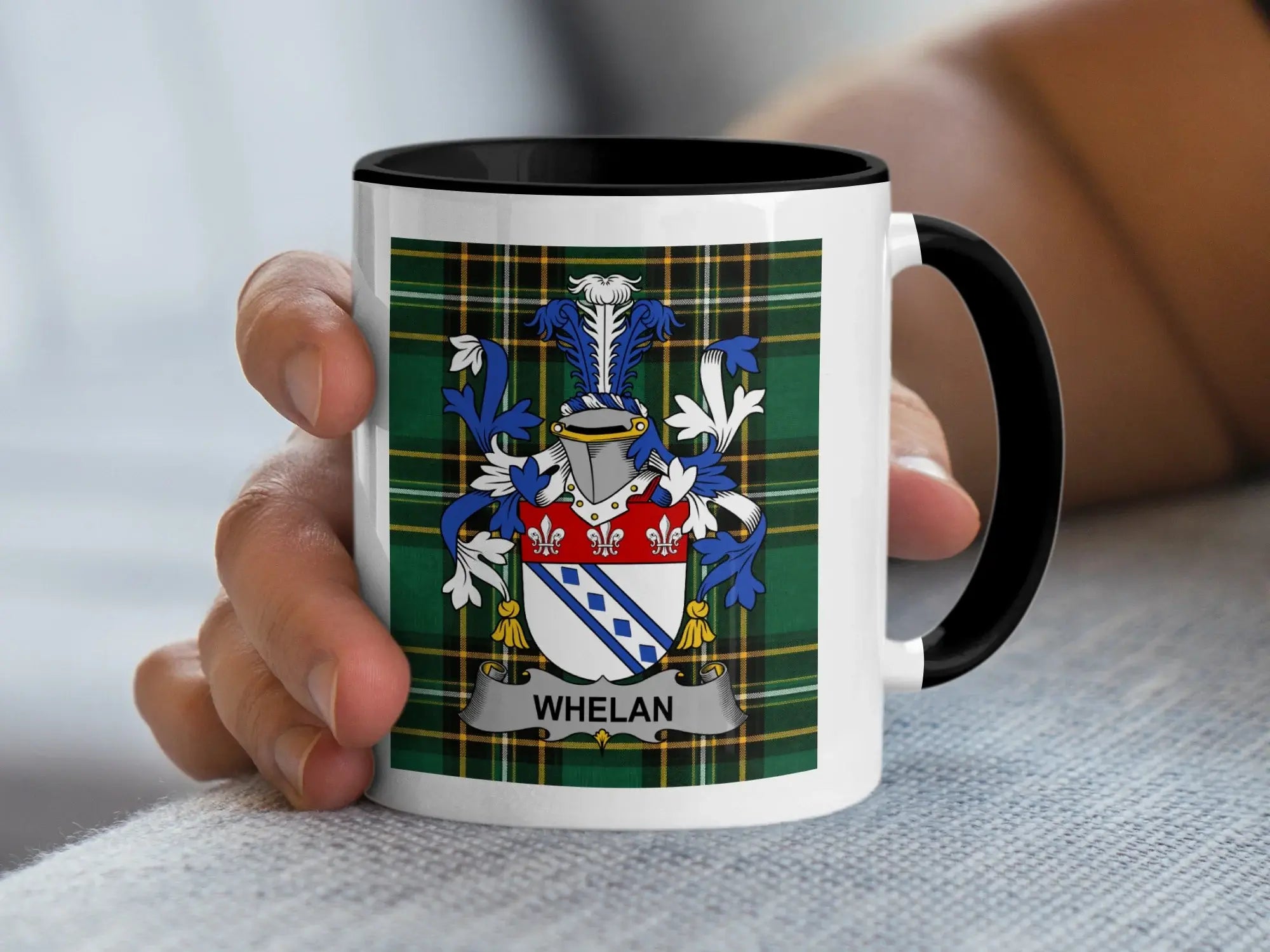 Mug with Whelan family crest on plaid background held by hand.