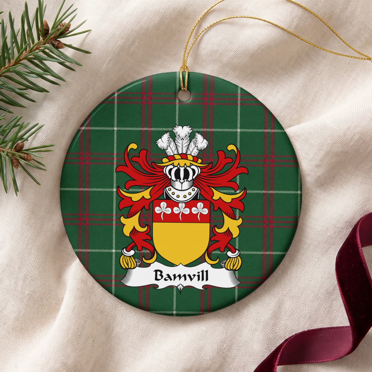 Bamvill ceramic ornament with gold string on cream fabric; three white trefoils on a red top band above a gold shield on Welsh national tartan.