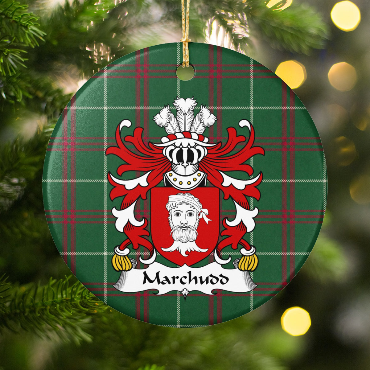 Marchudd ornament hanging on a Christmas tree among green branches and warm lights, with a red shield with a white bearded head on Welsh national tartan.