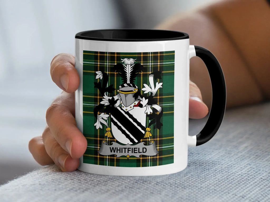 White mug with black rim featuring the Whitfield family crest on a plaid background.