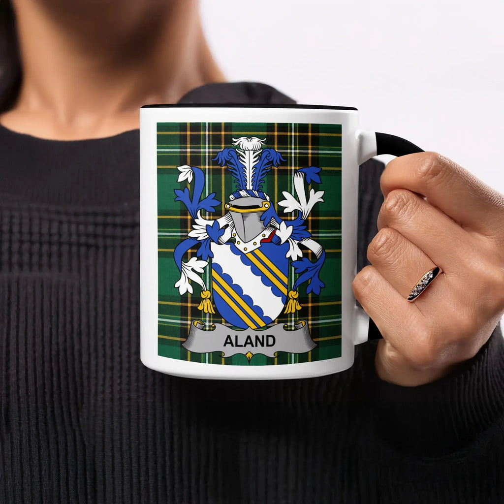 White mug with black handle featuring a green plaid background and the Aland coat of arms.