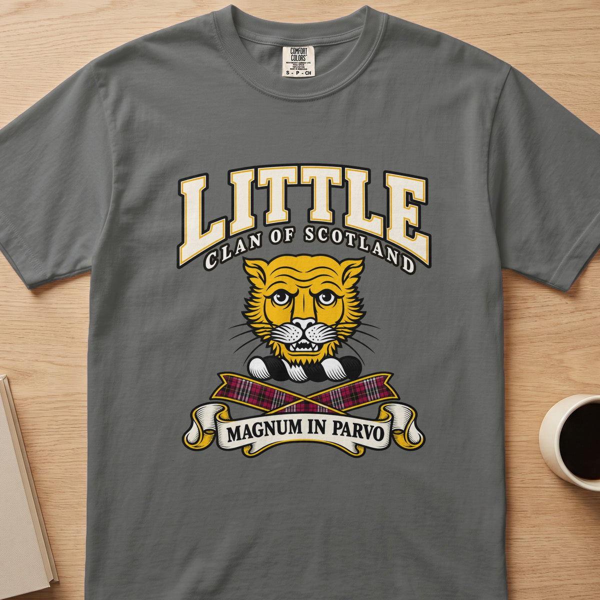 Little clan crest with gold cat face on a gray Comfort Colors T-shirt, front view