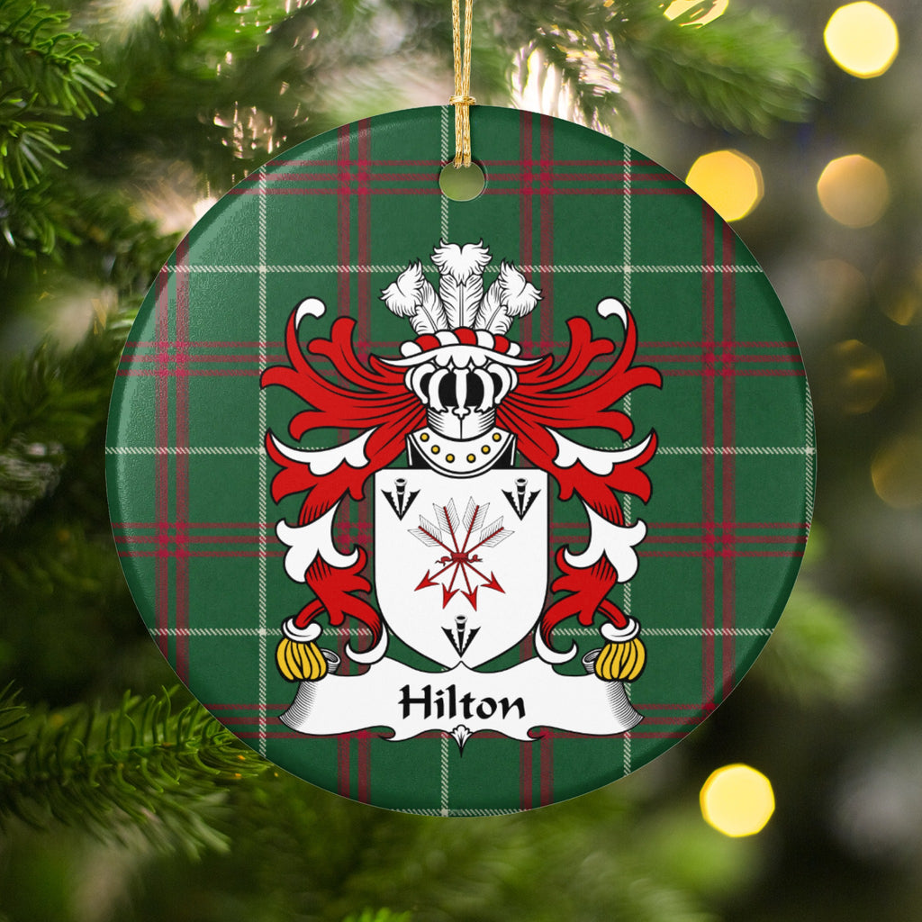 Hilton ornament hanging in a Christmas tree with warm lights; a tied bundle of arrows and three black arrowheads on a white shield on Welsh national tartan.