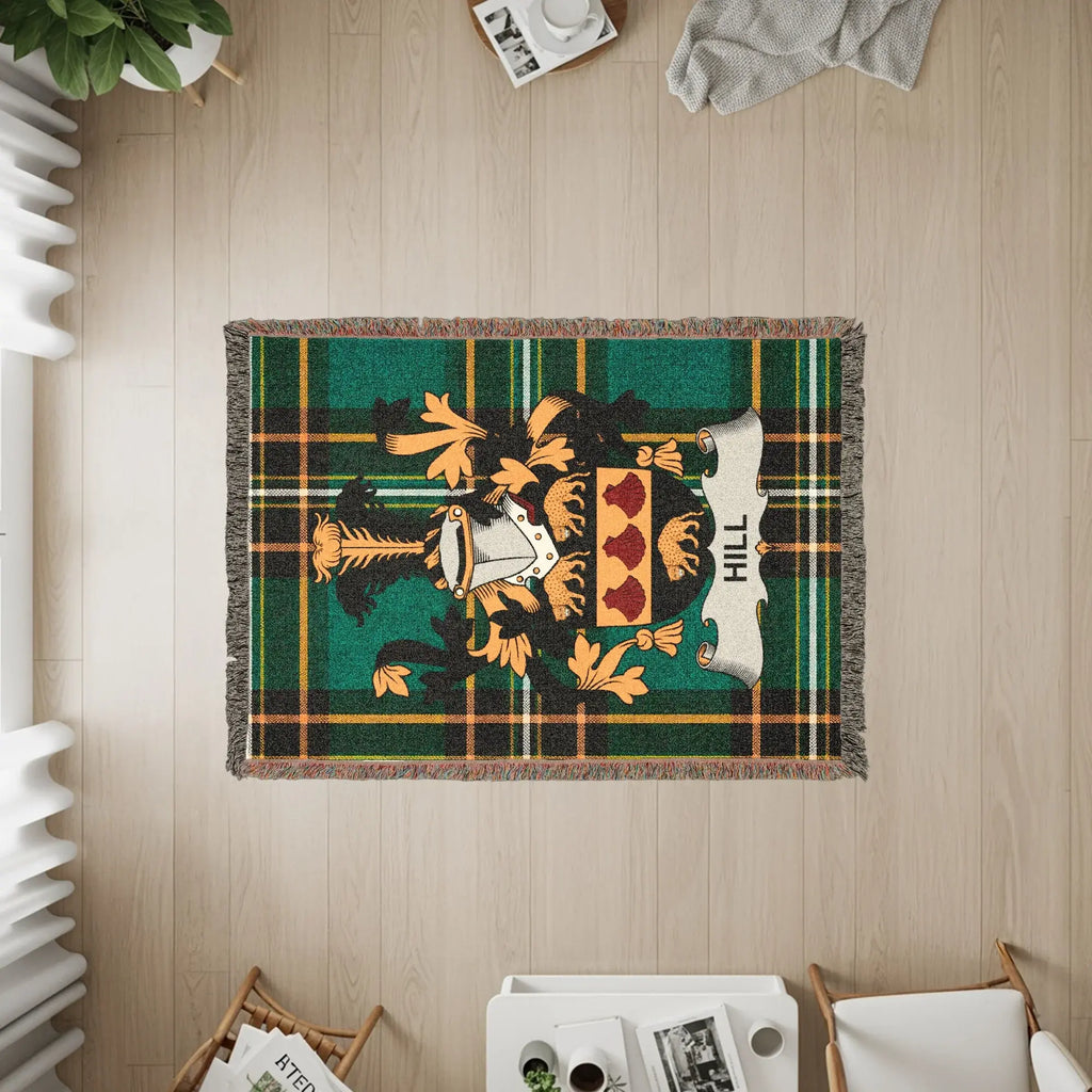 Green tartan woven blanket featuring the Hill family crest with a white scroll.
