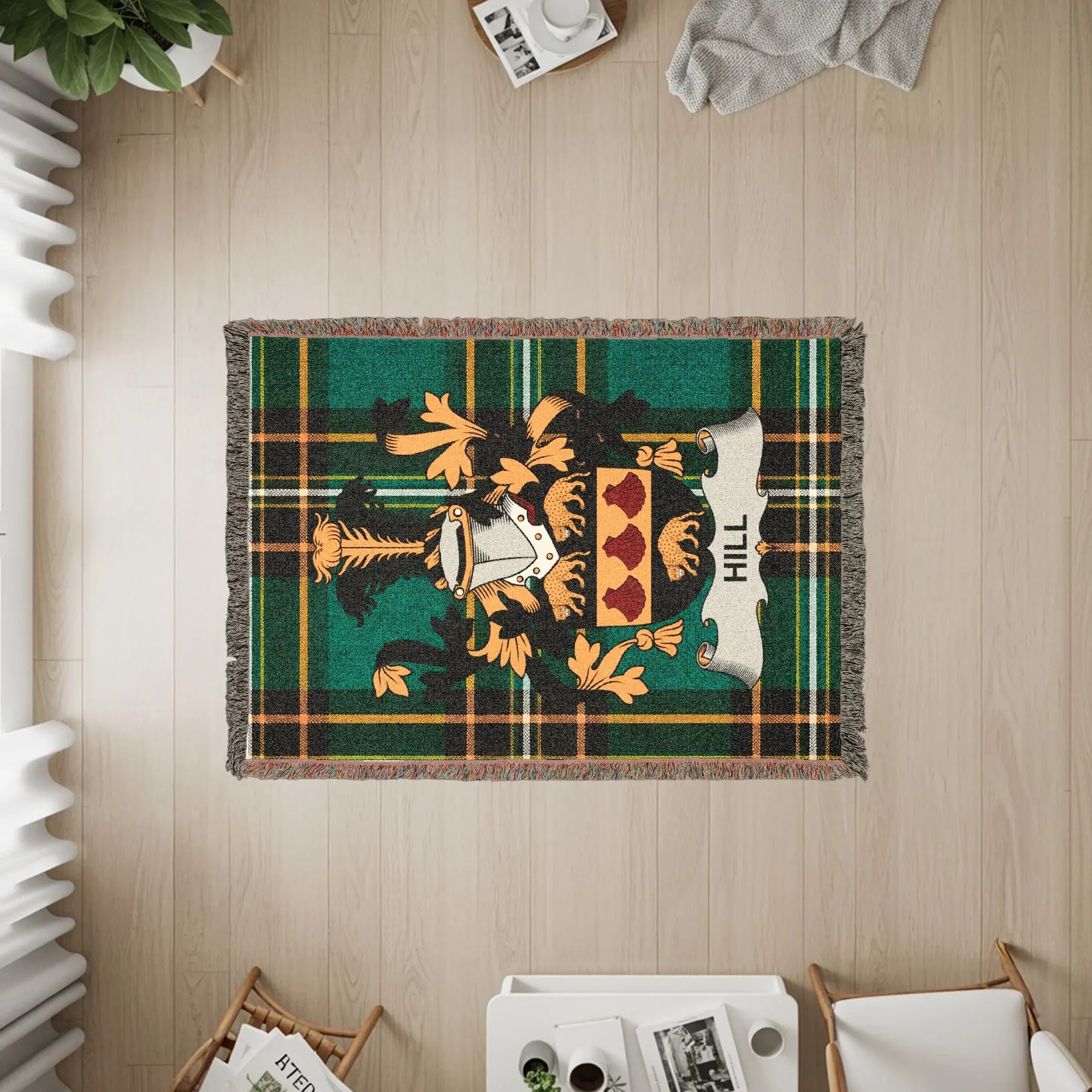 Green tartan woven blanket featuring the Hill family crest with a white scroll.