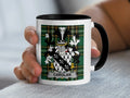 White mug with black handle featuring green plaid and the CAROLAN family crest.
