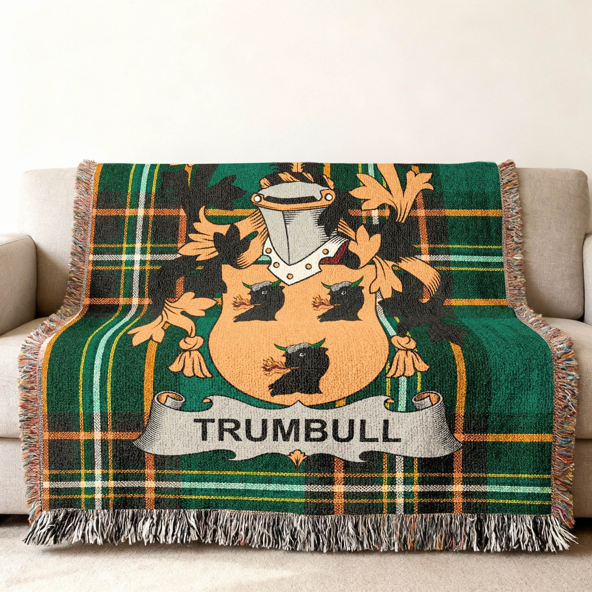 Green tartan blanket with Trumbull family crest draped on a sofa.
