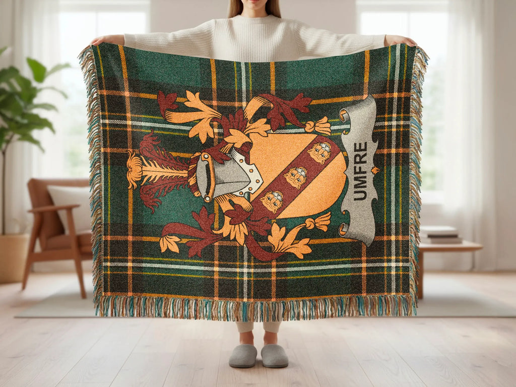 Tartan blanket with UMFRE crest and fringed edges, held by a person.