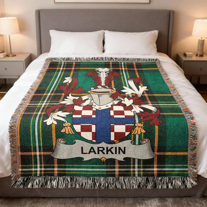 Plaid blanket with Larkin family crest on a bed.