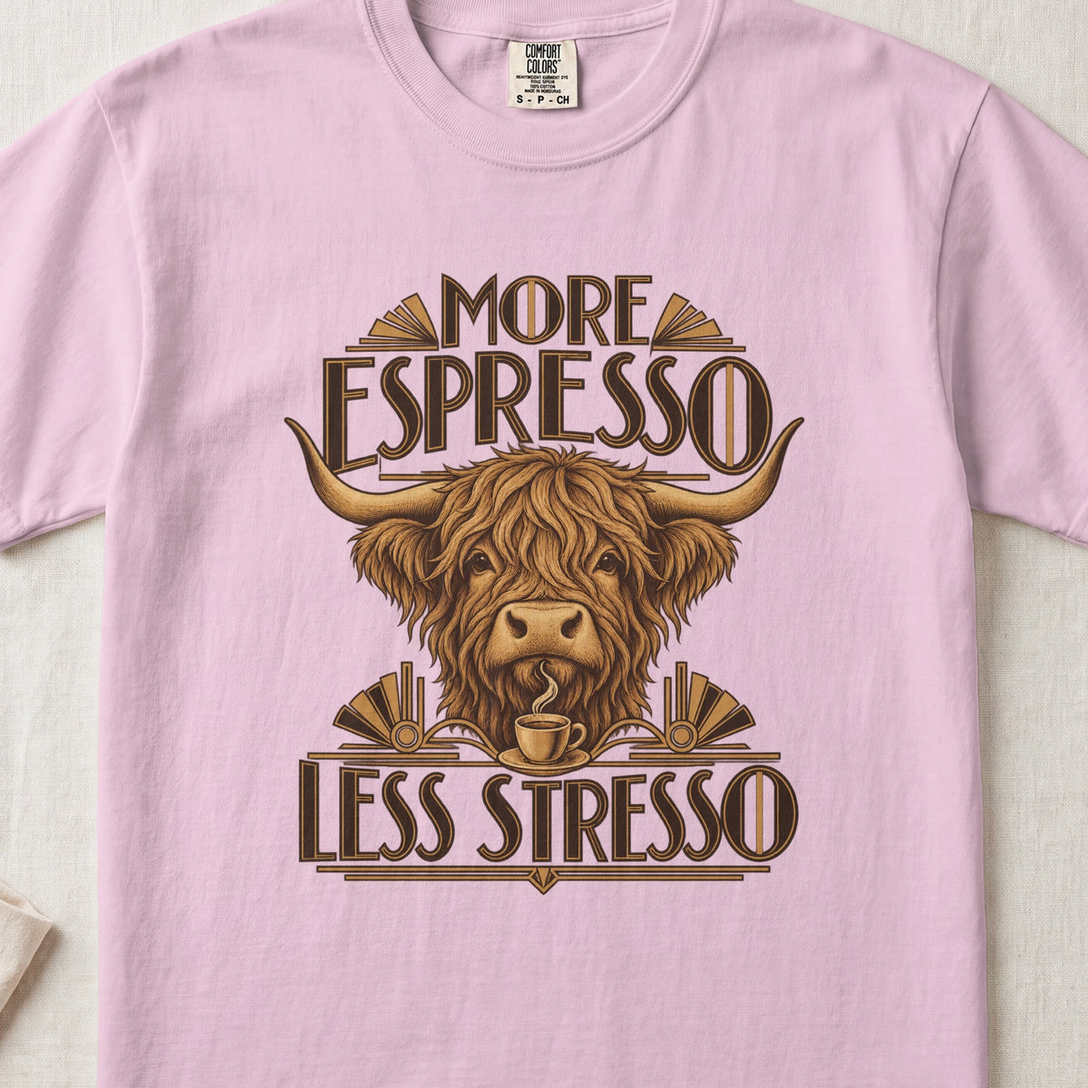 More Espresso, Less Stresso Highland cow design on a Blossom Comfort Colors 1717 T-shirt, flat lay