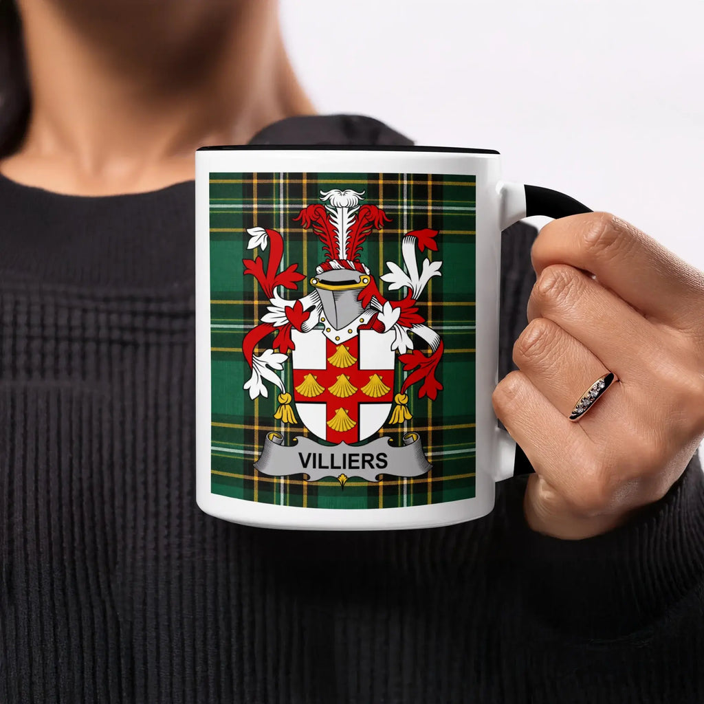 Mug with Villiers family crest on plaid background held by a person.