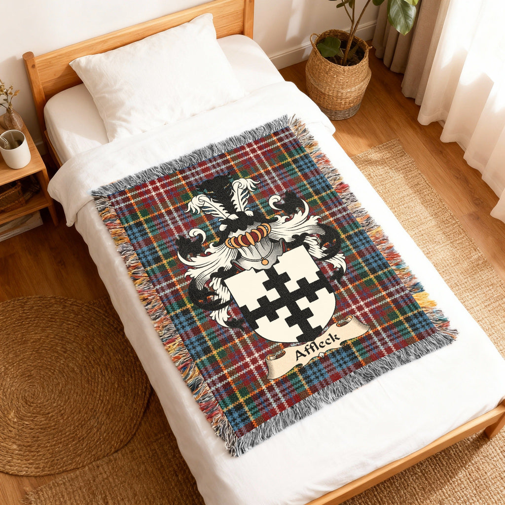 Affleck Scottish family shield woven blanket with Caledonia tartan background, displayed on a bed