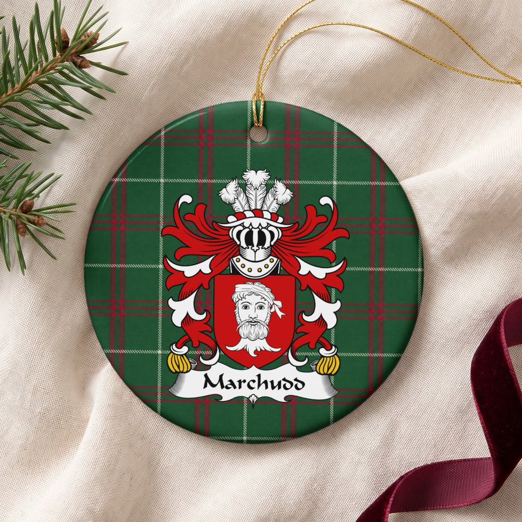 Marchudd ornament on cream fabric with gold hanging string, evergreen and burgundy ribbon; a red shield with a white bearded head on Welsh national tartan.
