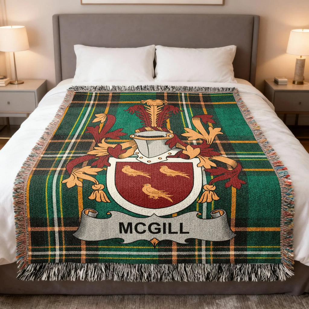McGill family crest on a green and black tartan throw blanket on a bed.