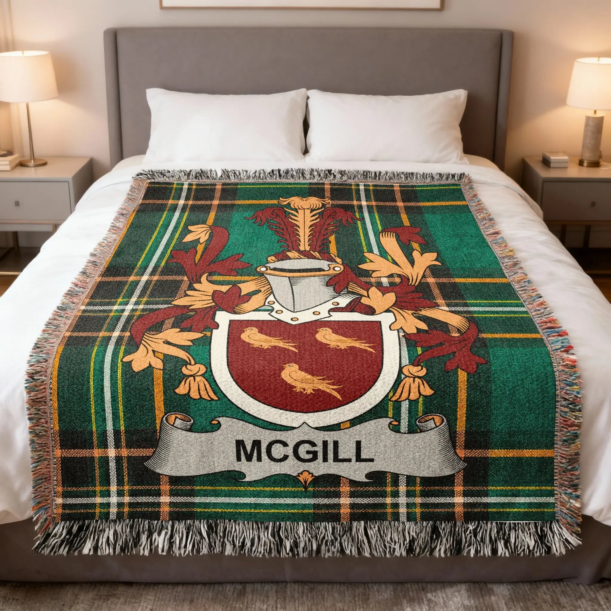 McGill family crest on a green and black tartan throw blanket on a bed.