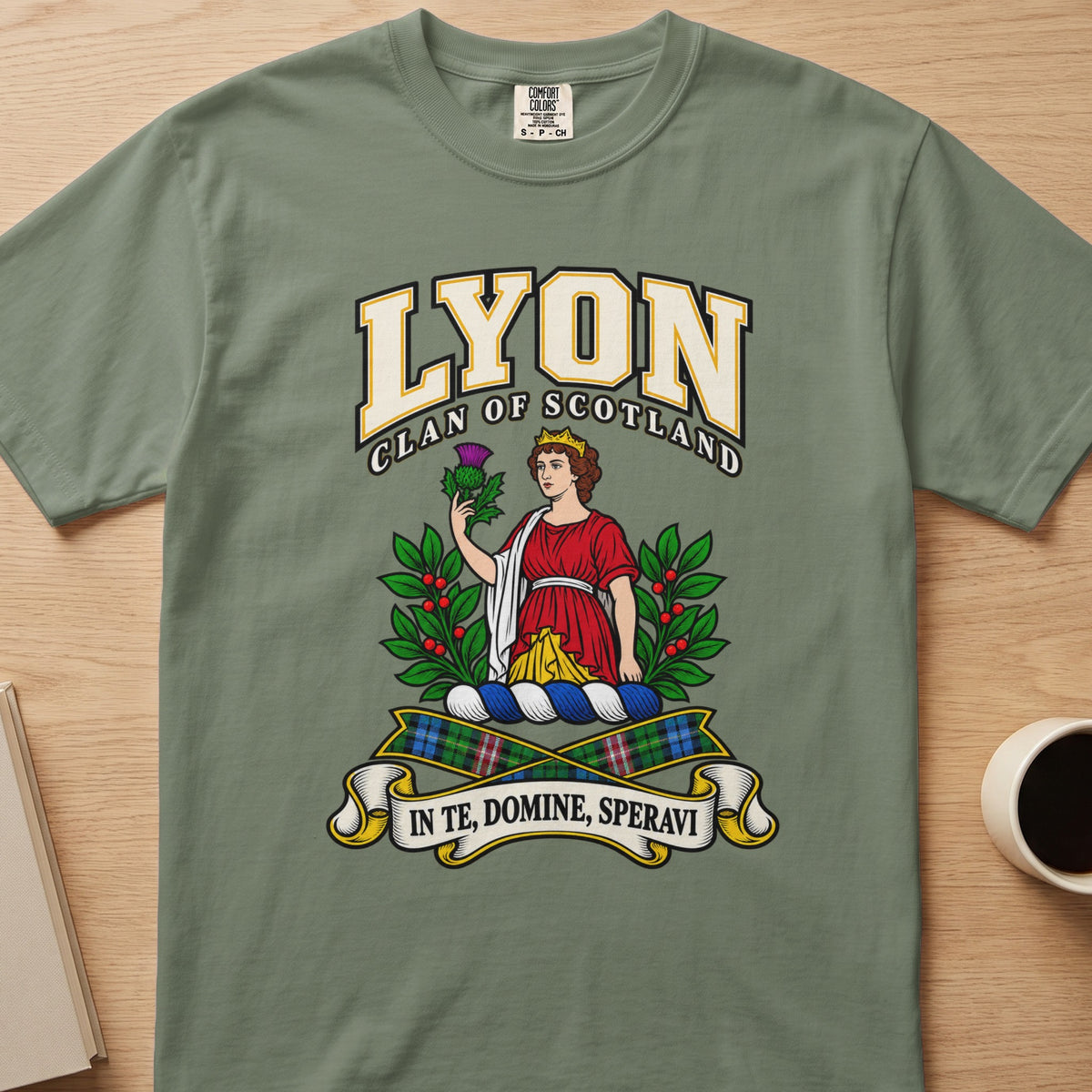 Lyon red-clad figure framed by green branches graphic on a sage green Comfort Colors T-shirt, front view