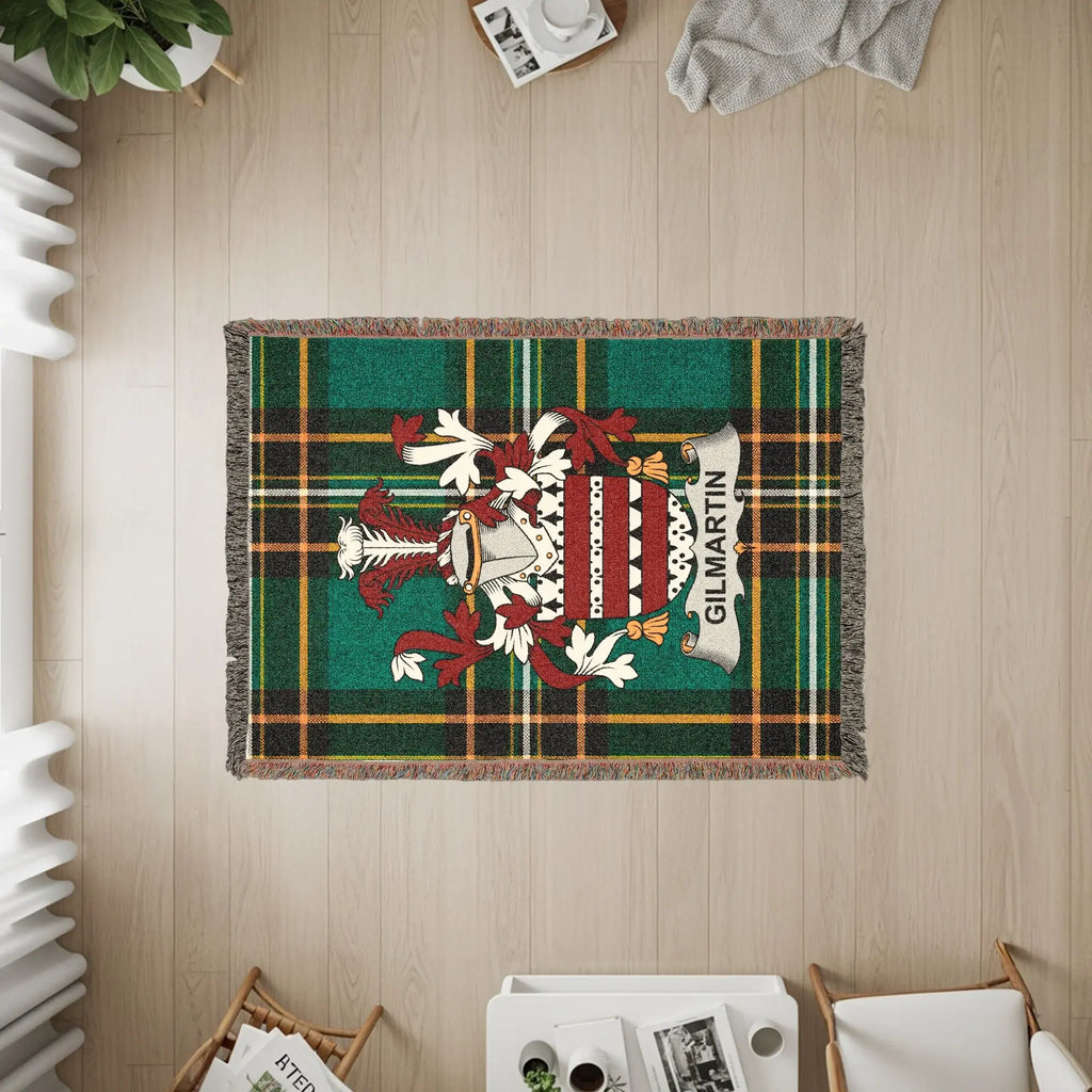 Green and red plaid throw blanket with GILMARTIN crest, draped on floor.