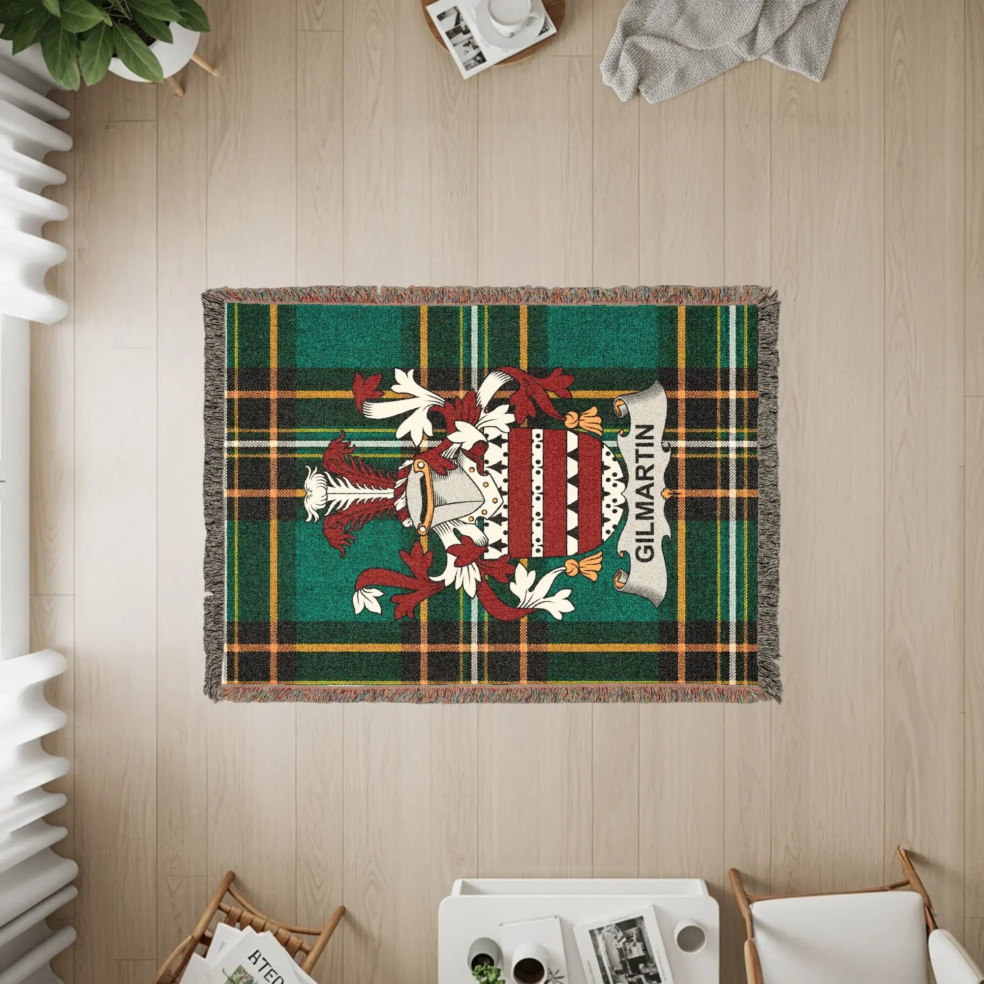Green and red plaid throw blanket with GILMARTIN crest, draped on floor.