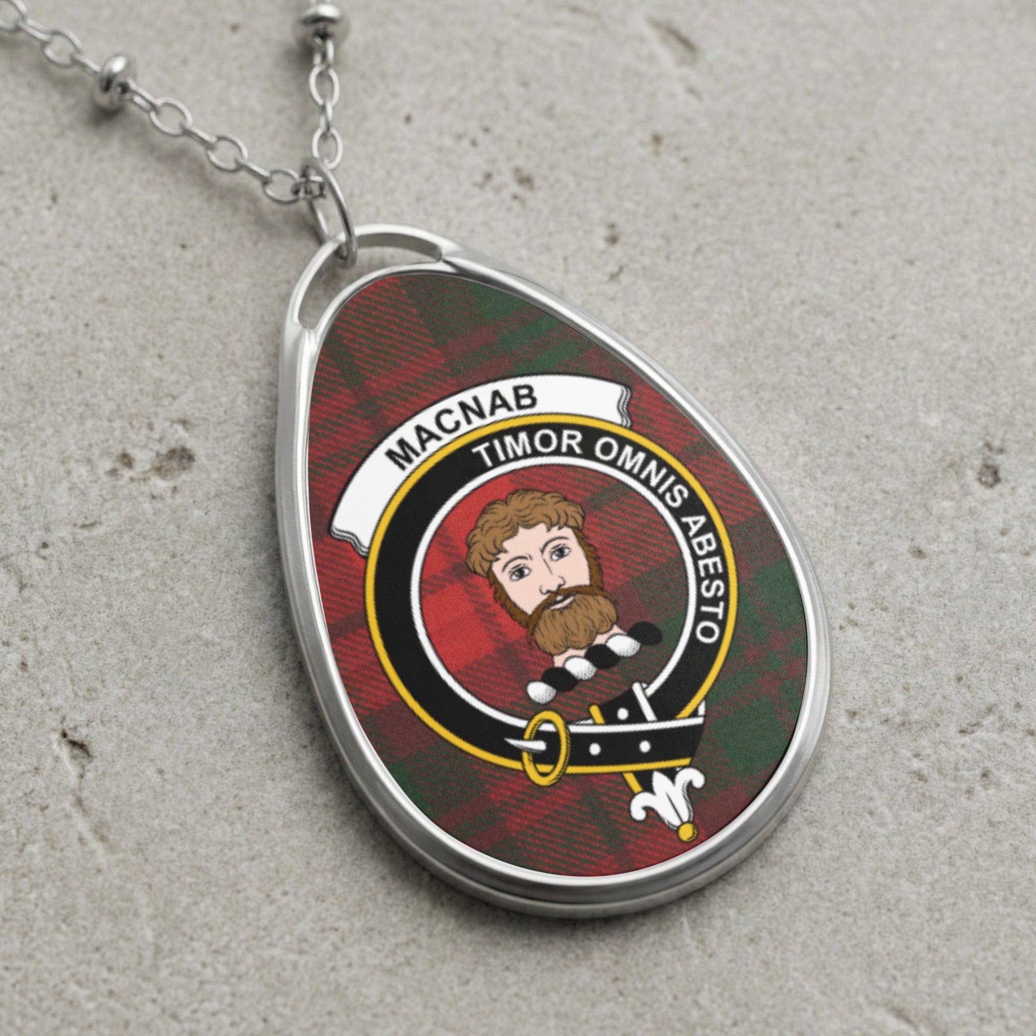 Oval clan crest pendant with tartan background and motto "Timor Omnis Abesto".