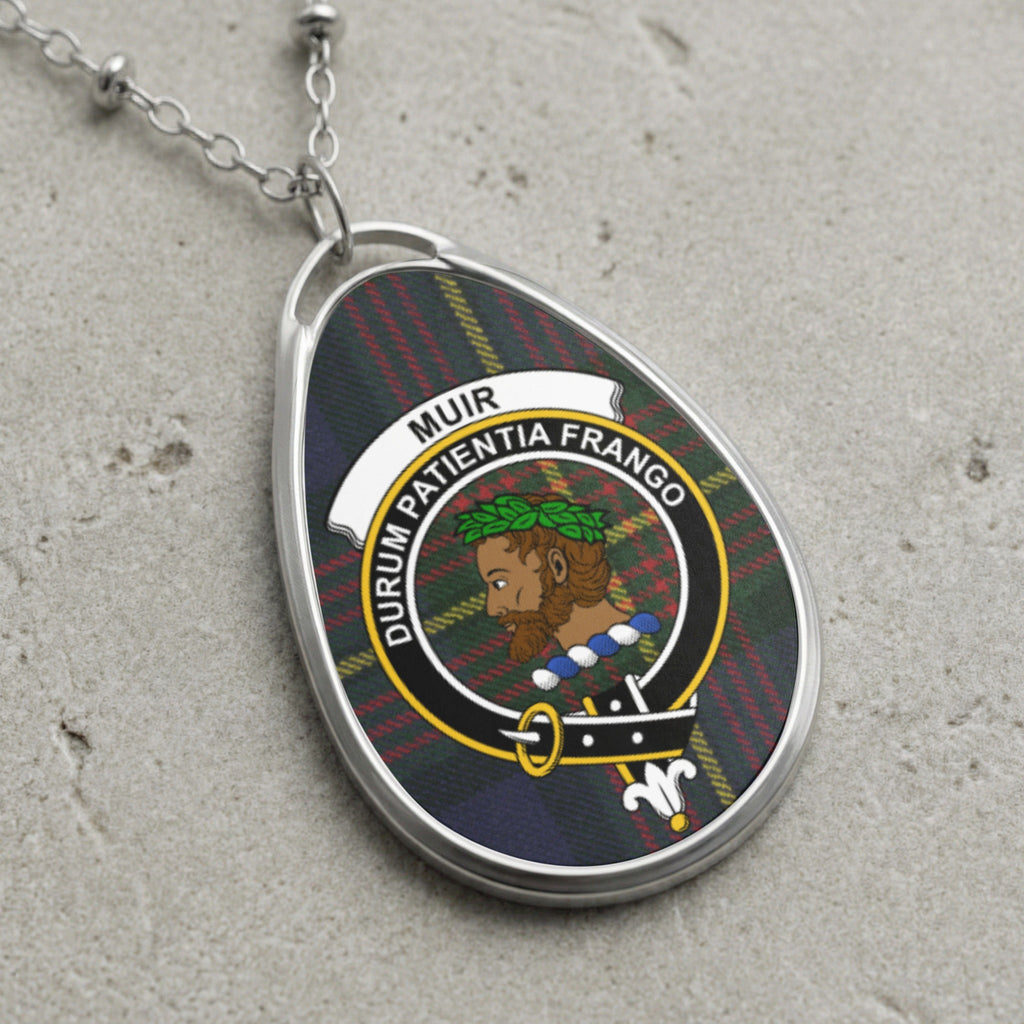 Silver oval pendant with Muir clan crest on tartan background with Latin motto.