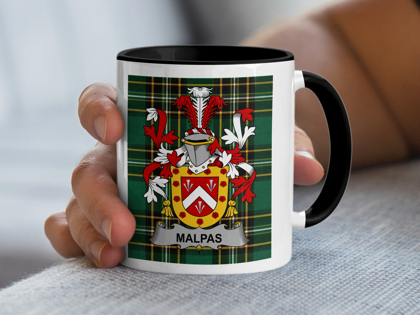 White mug with black handle, featuring Malpas family crest on plaid background.