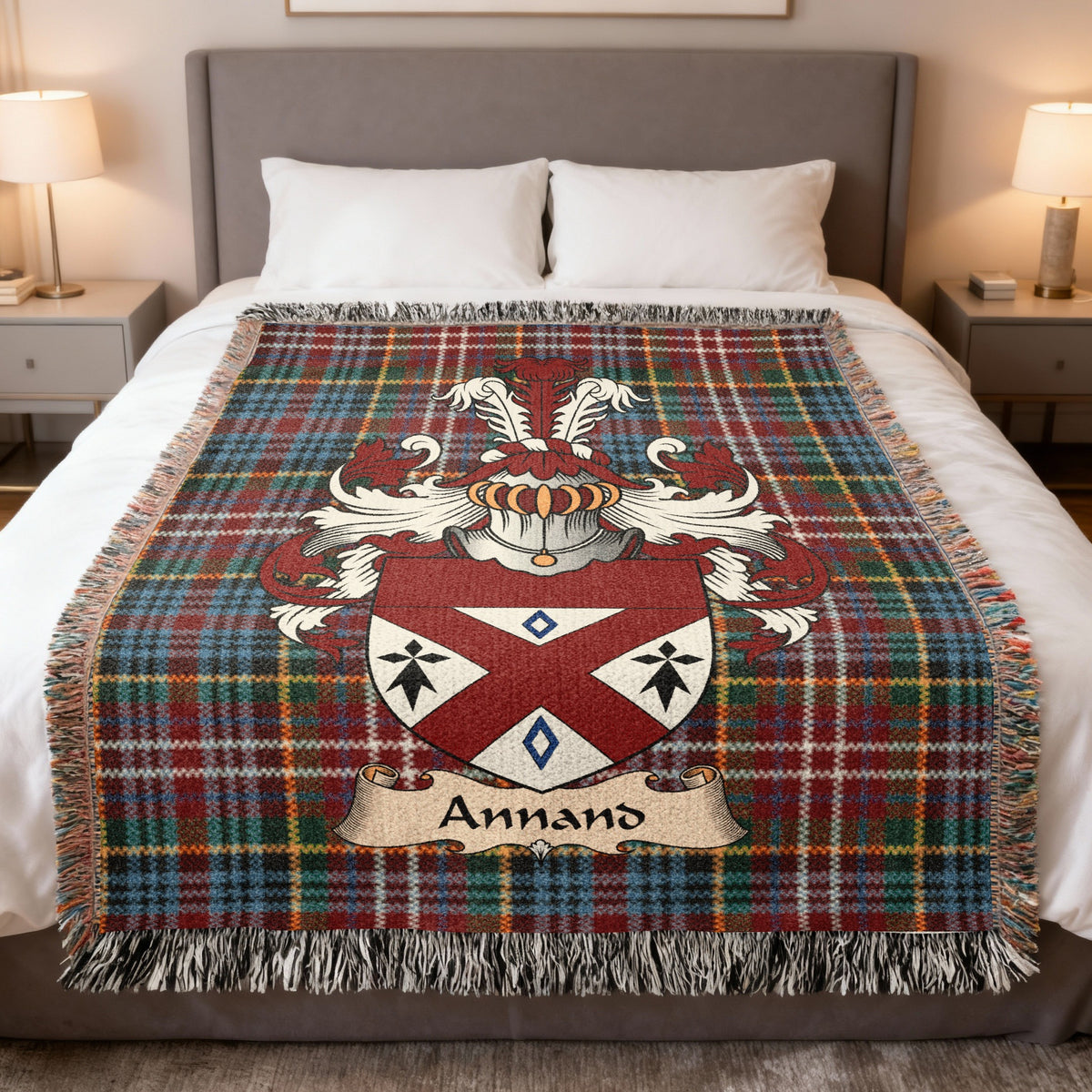 Annand Scottish family crest woven blanket on a Caledonia tartan background, displayed on a bed