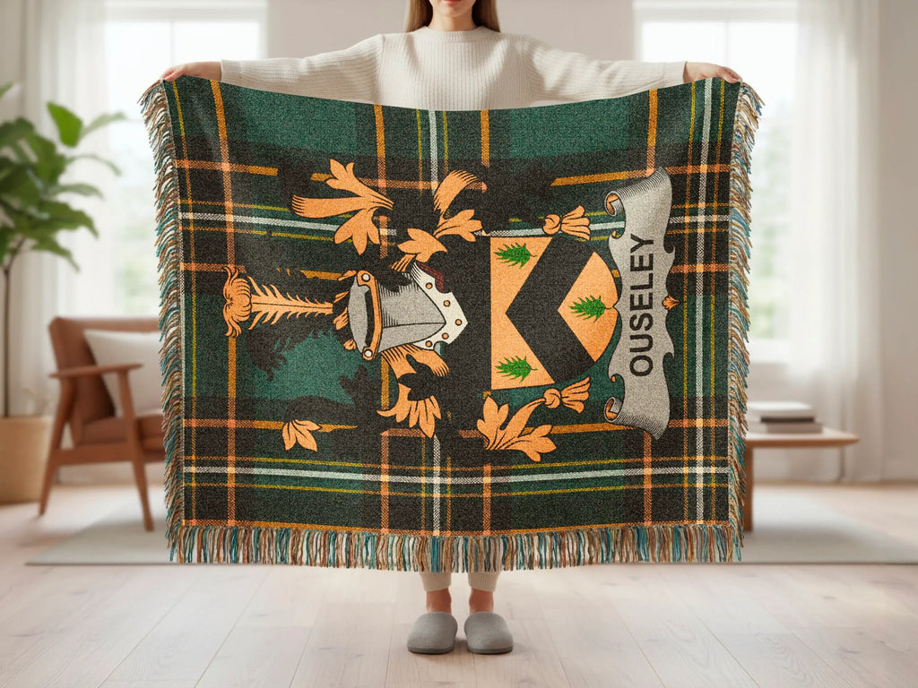 Tartan throw blanket with Ouseley crest and fringe, held by a person.